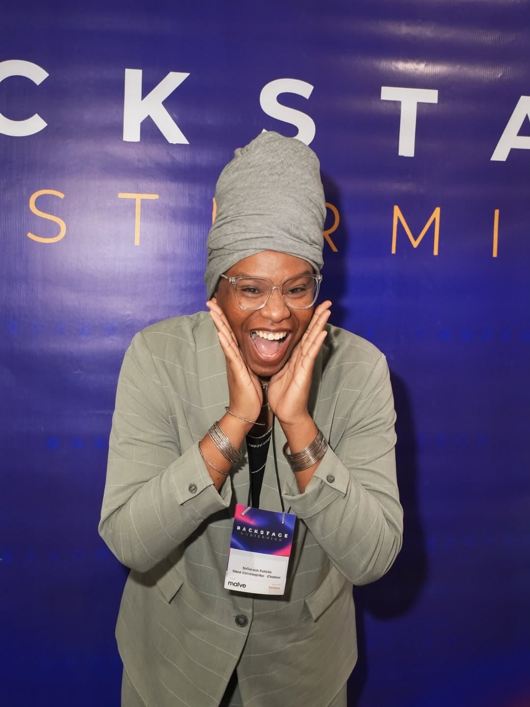 Participante sorrindo diante do painel de identidade do Backstage Mastermind 2026.